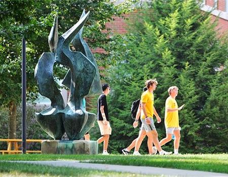 Students walking on campus near flame statue