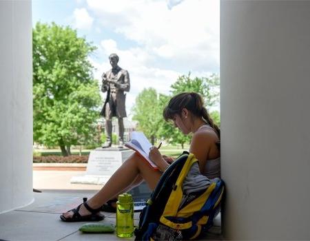 Student studying at outside library in front of Lincoln statute